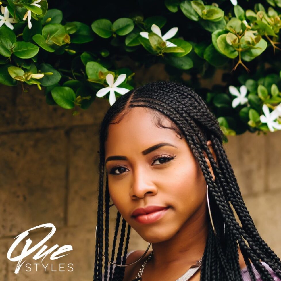 Portrait of a young woman with braided hair and a flowered background.