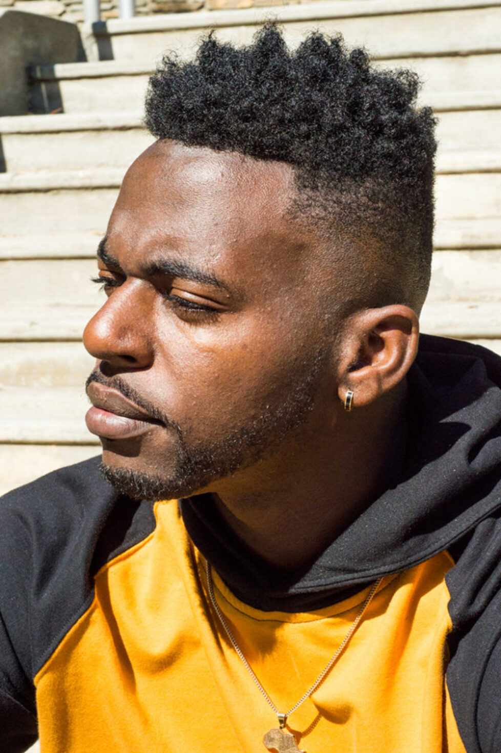 Man with a thoughtful expression wearing a yellow and black jacket.